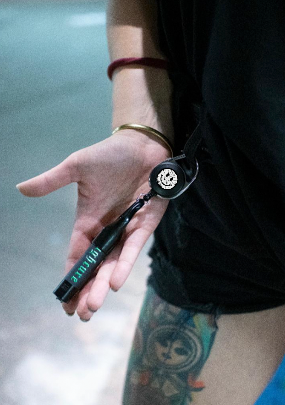 Hand hält den Clipper Halter mit eingesetztem Feuerzeug, der Karabiner hängt an der Kleidung